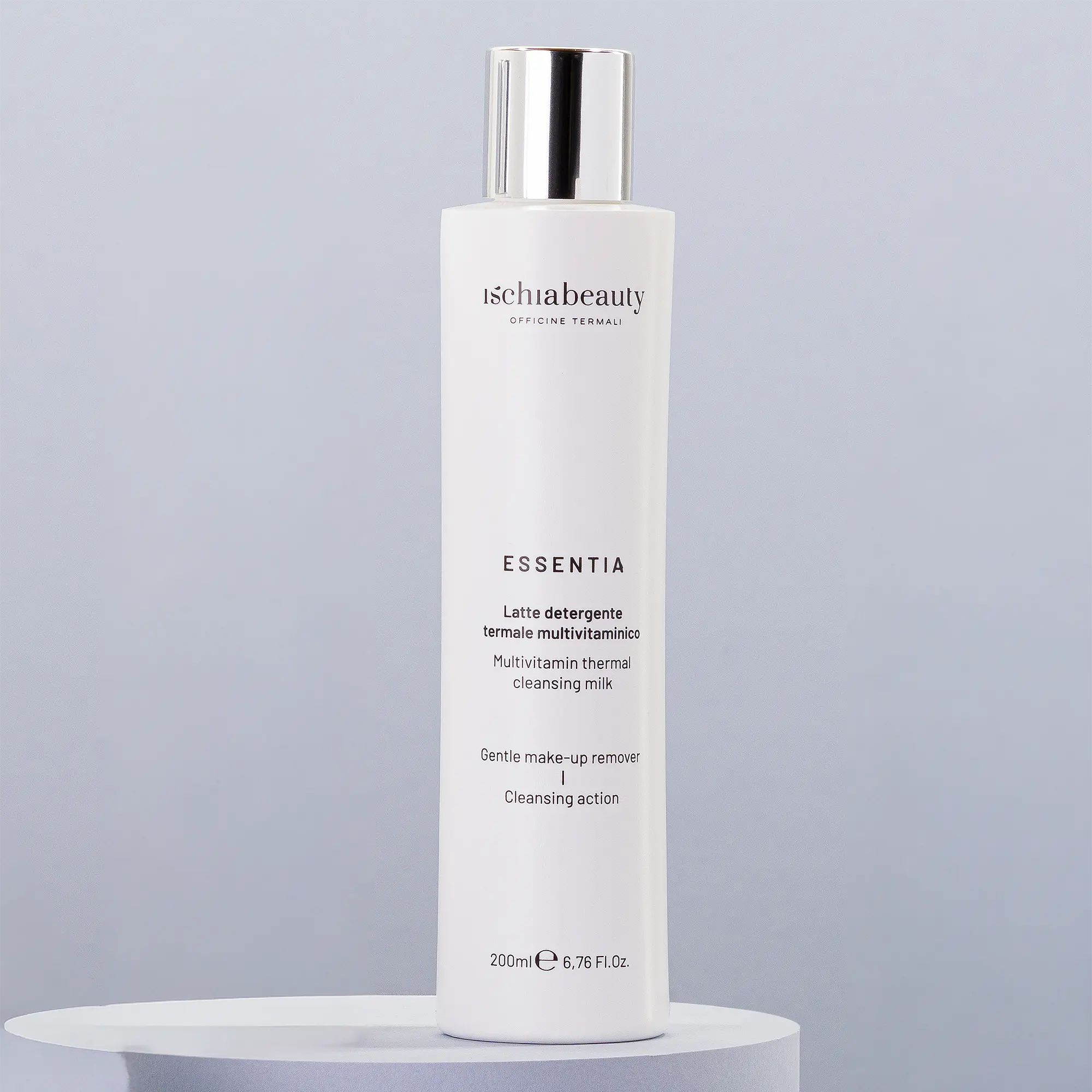 Flacone bianco con tappo argentato e testo. Nome prodotto: Latte detergente termale multivitaminico. Su piedistallo chiaro.