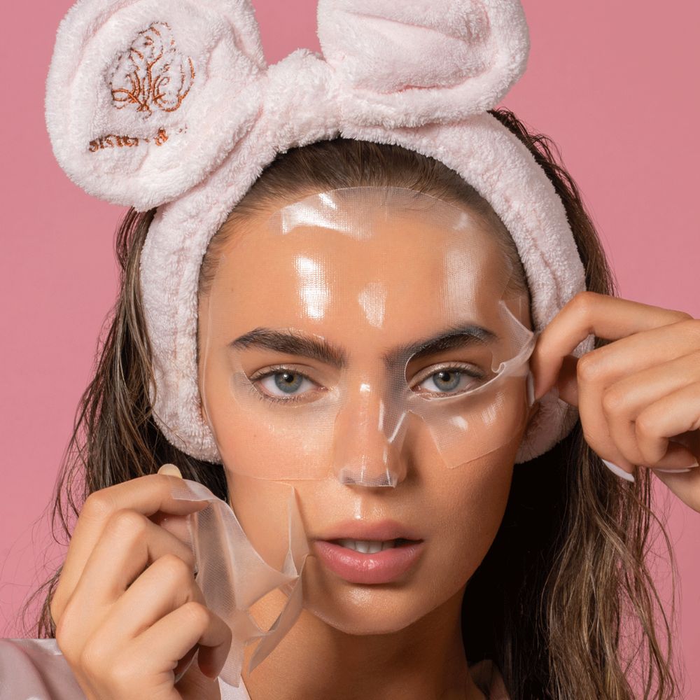 Donna con maschera viso, che rimuove una maschera trasparente. Fascia rosa.