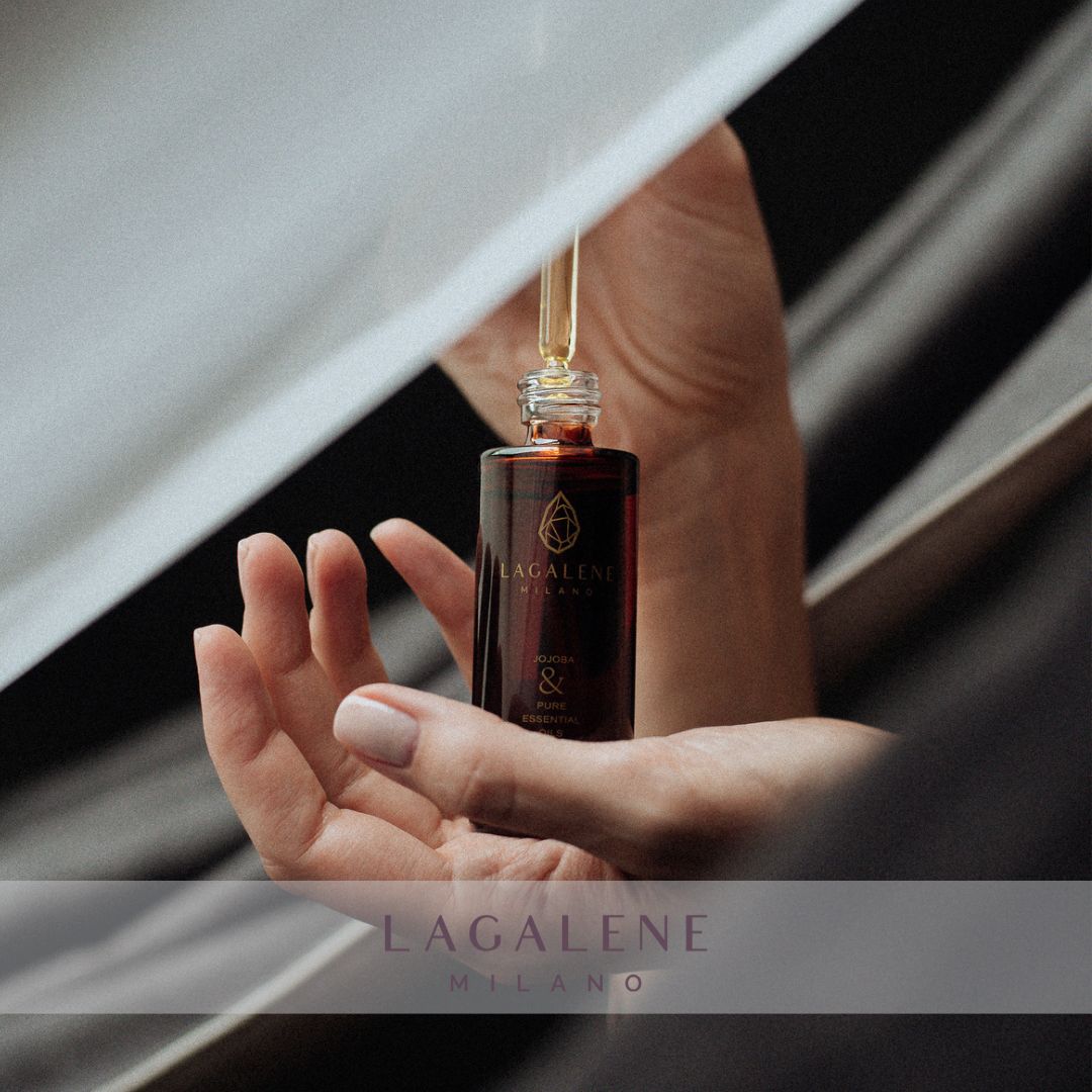 Flacone di vetro marrone di Lagalene Milano con contagocce dorato, tenuto in una mano. L'etichetta recita "Jojoba & Pure Essential Oils".