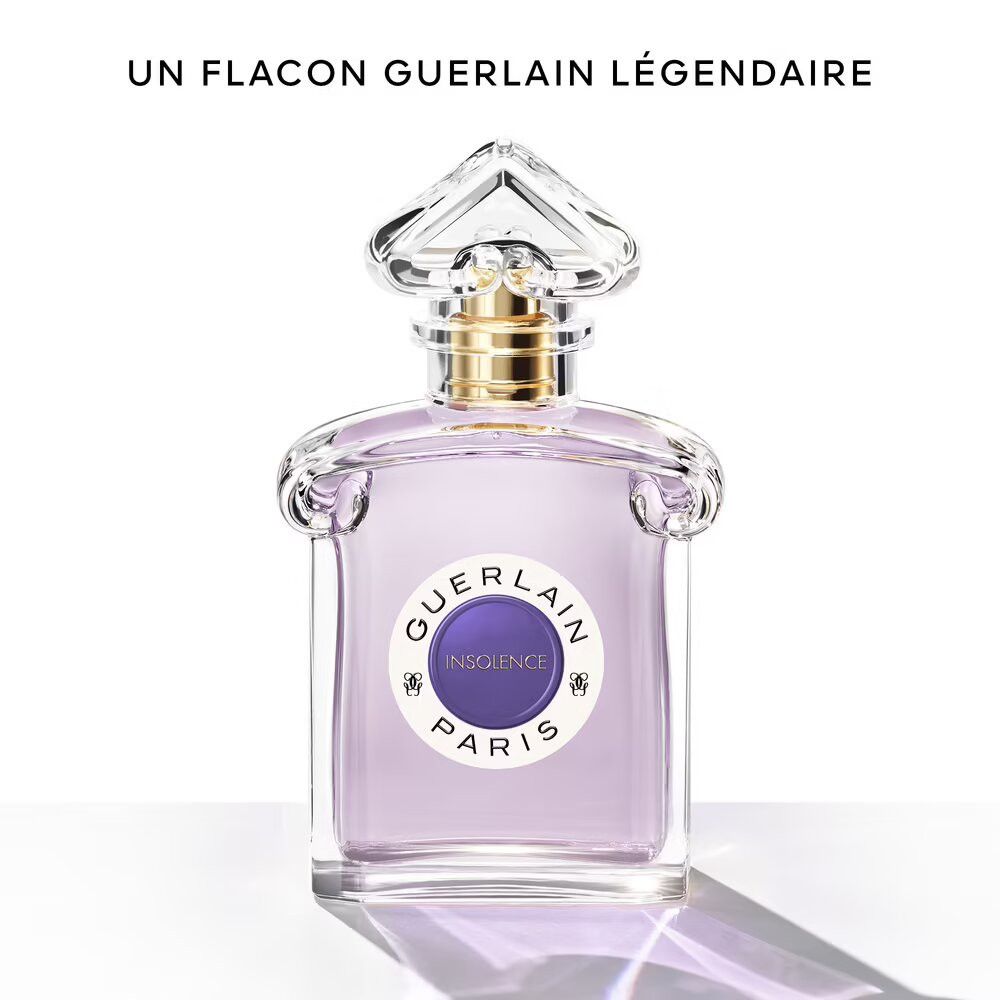 Flacone in vetro con liquido viola. Etichetta "INSOLENCE PARIS". Tappo dorato. Spruzzatore trasparente. Testo: "UN FLACON GUERLAIN LÉGENDAIRE".