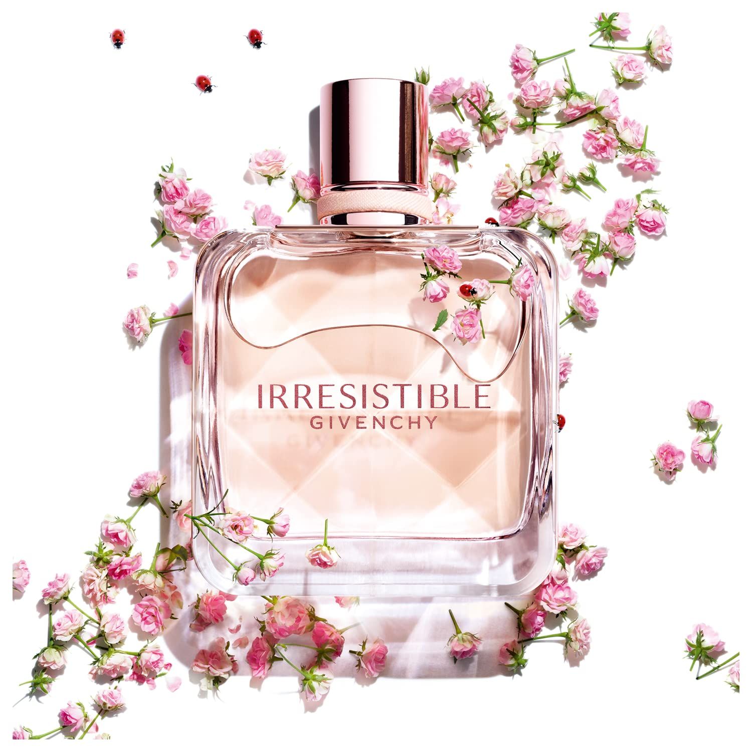 Flacone quadrato, contenuto rosa, circondato da piccoli fiori rosa e coccinelle. Scritta: Irresistible Givenchy.