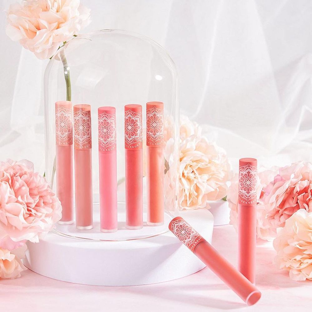 Diversi rossetti su un piedistallo. Alcuni in una cupola di vetro. Fiori sullo sfondo.