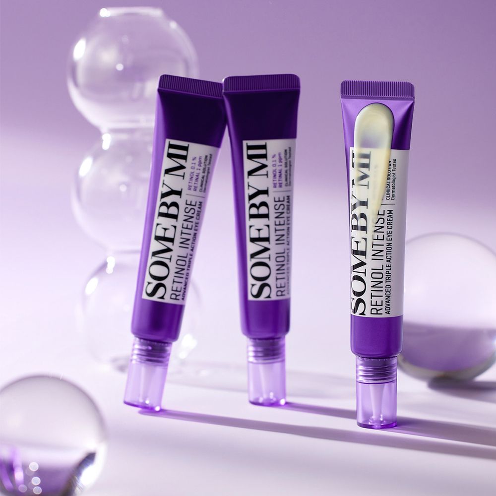 Tre tubetti di crema contorno occhi SOMEBYMI Retinol Intense su sfondo viola con sfere di vetro.