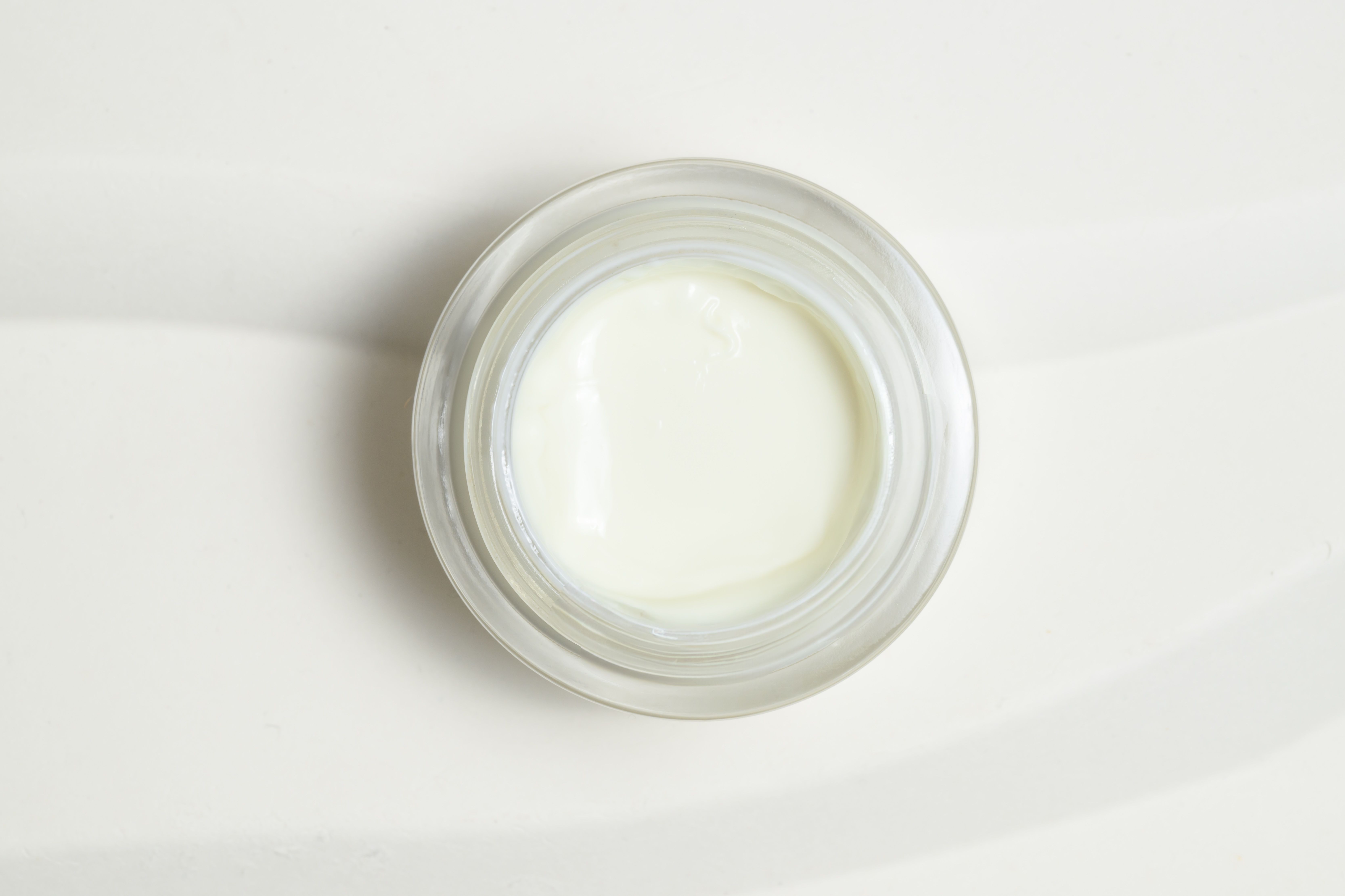 Vaso di vetro con crema bianca. Vista dall'alto.