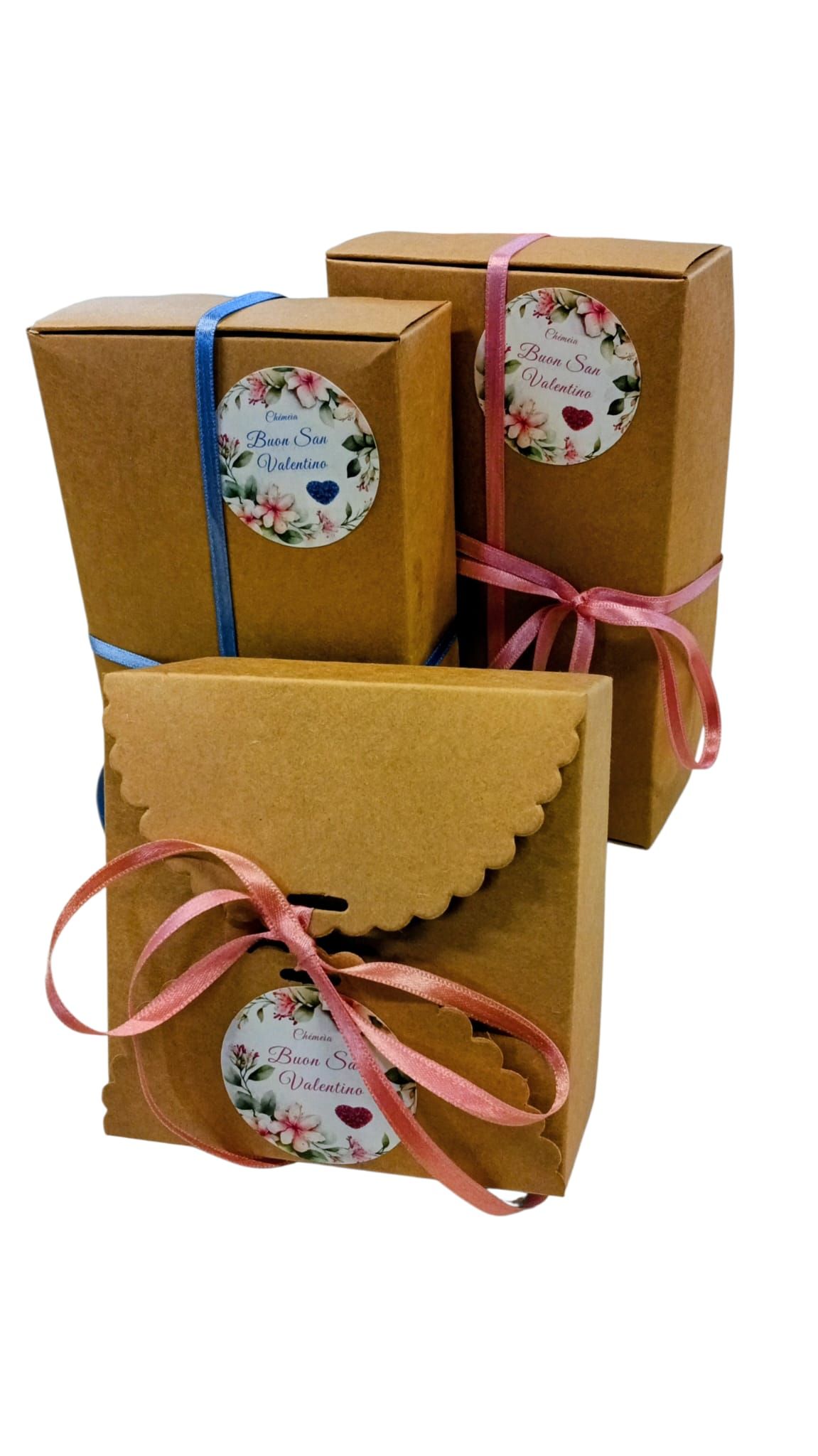 Tre scatole regalo marroni con fiocchi e adesivi. Adesivi con motivo floreale e testo.