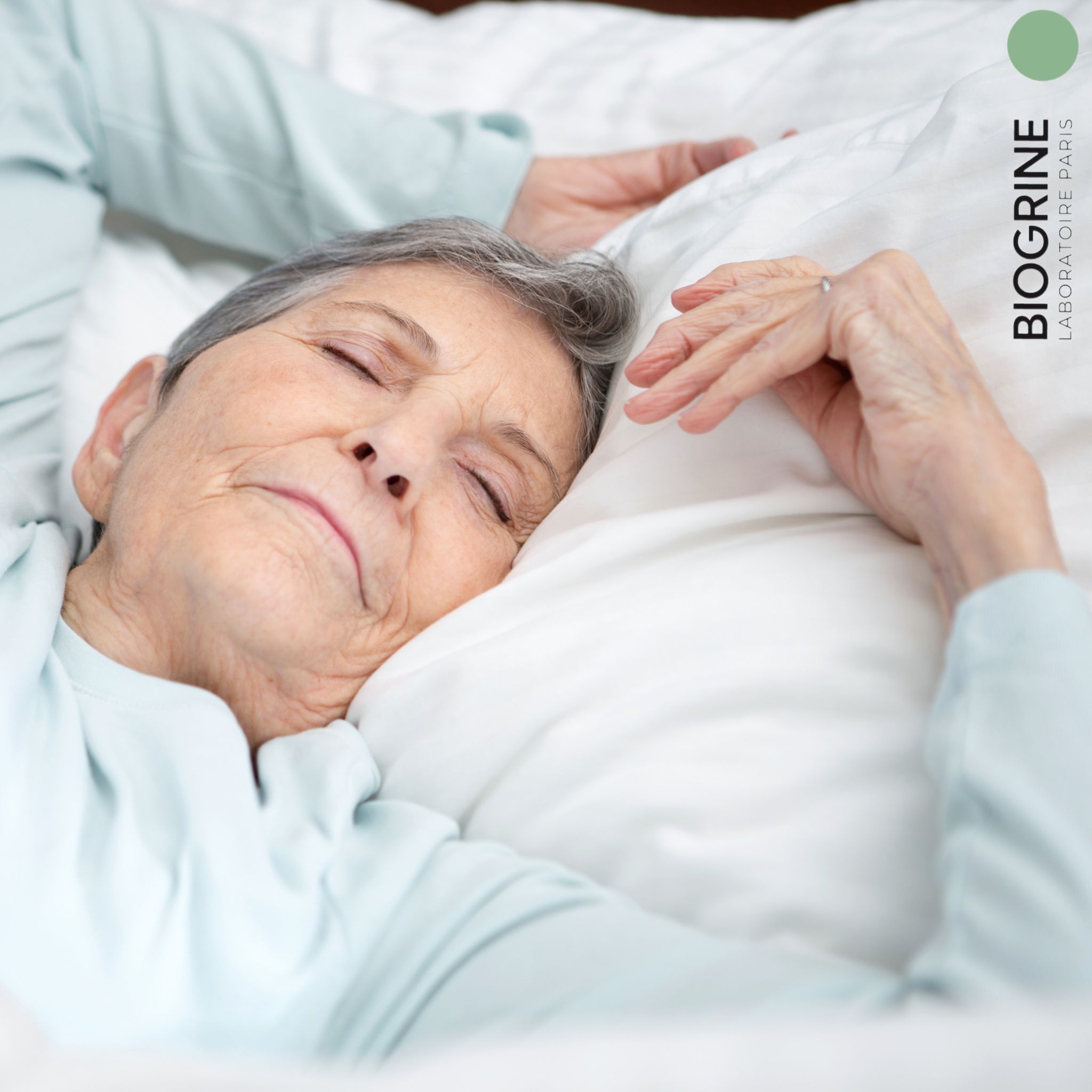 Donna anziana che dorme su un cuscino. Logo BIOGRINE.