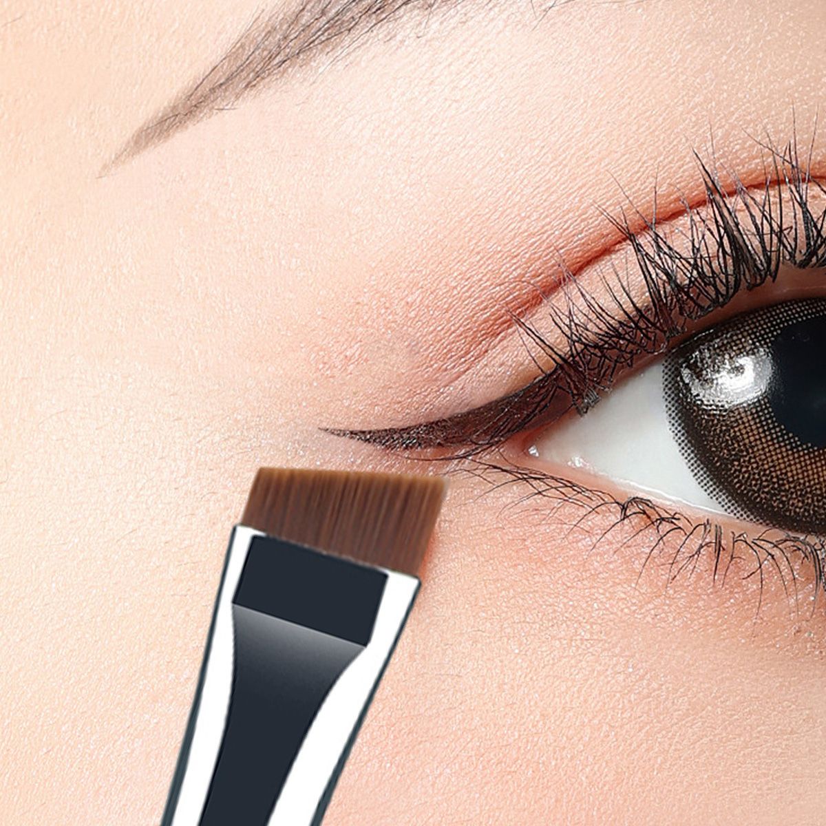 Un pennello angolato per il trucco degli occhi applicato su un occhio per disegnare l'eyeliner.
