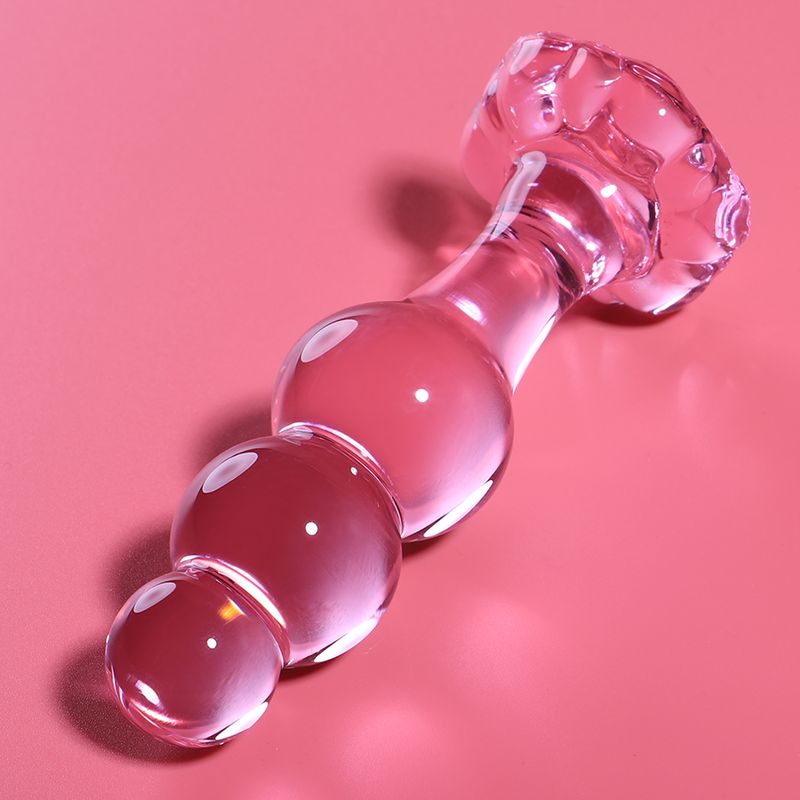 Plug anale in vetro rosa con segmenti sferici, su sfondo rosa.