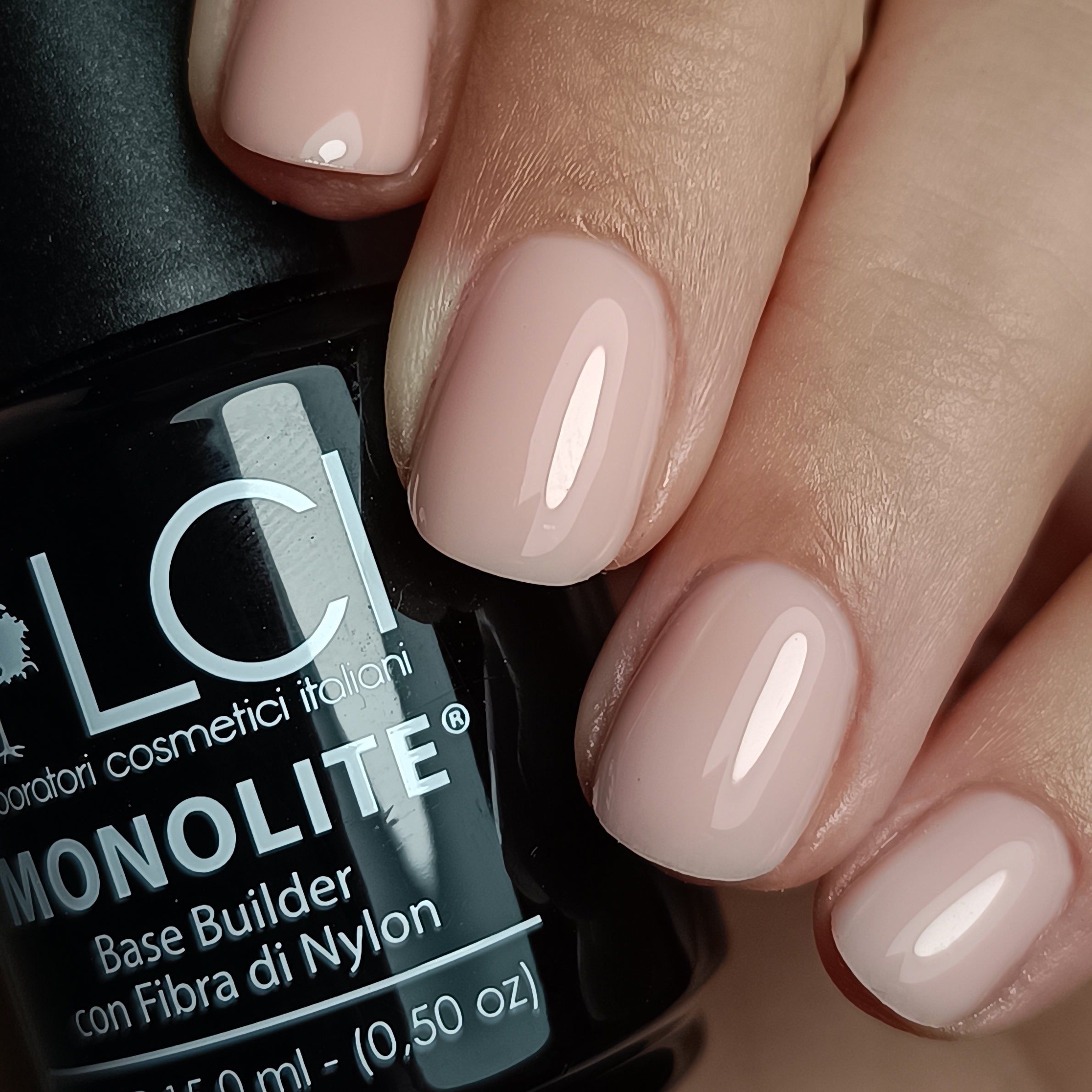 LCI Cosmetics MONOLITE Fiber Base applicata sulle unghie. Tonalità rosa. Flacone nero sullo sfondo.