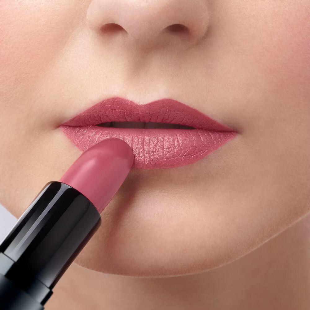 Labbra dipinte con rossetto rosa. Porta rossetto nero.