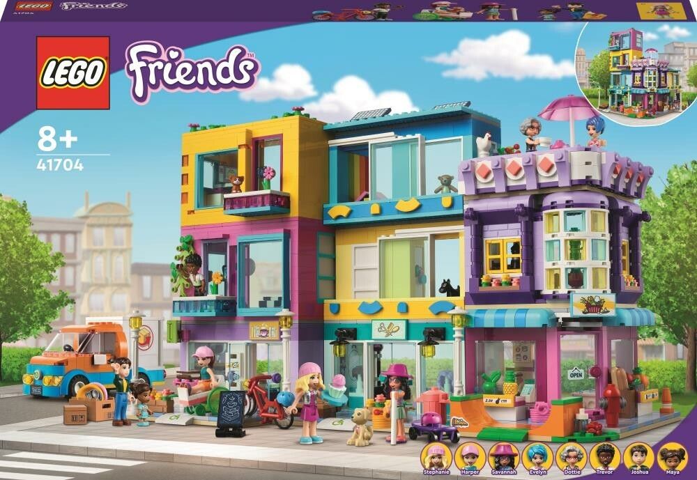 Set di costruzione LEGO Friends Edificio della Strada Principale. La confezione mostra un edificio colorato con negozi e appartamenti. Il set è adatto a bambini dagli 8 anni in su. Include personaggi e accessori. Il set è confezionato in una scatola.