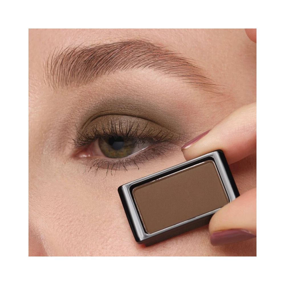 Artdeco Lidschatten Matt 520 Light Grey Mocha. Ombretto marrone in un contenitore nero, tenuto davanti a un occhio.