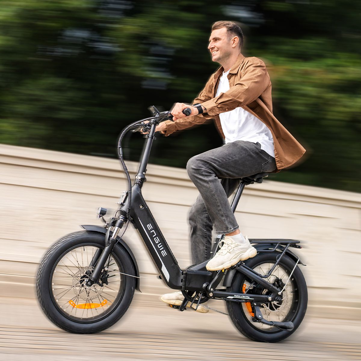 Uomo in sella a una bicicletta elettrica nera. Il logo ENGWE è visibile. Lo sfondo è sfocato.