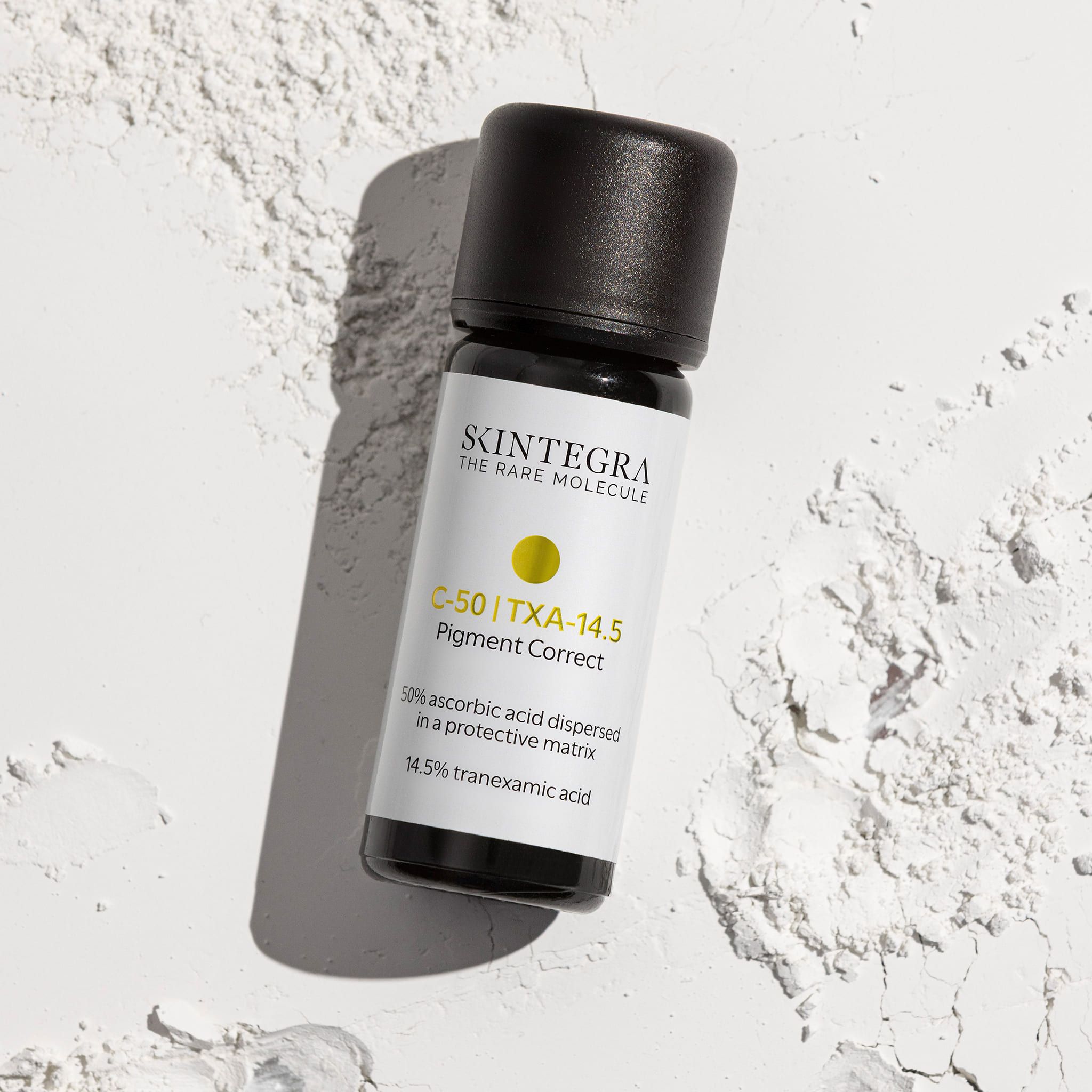 Flacone di siero Skintegra C-50 | TXA-14.5 Pigment Correct su polvere bianca.