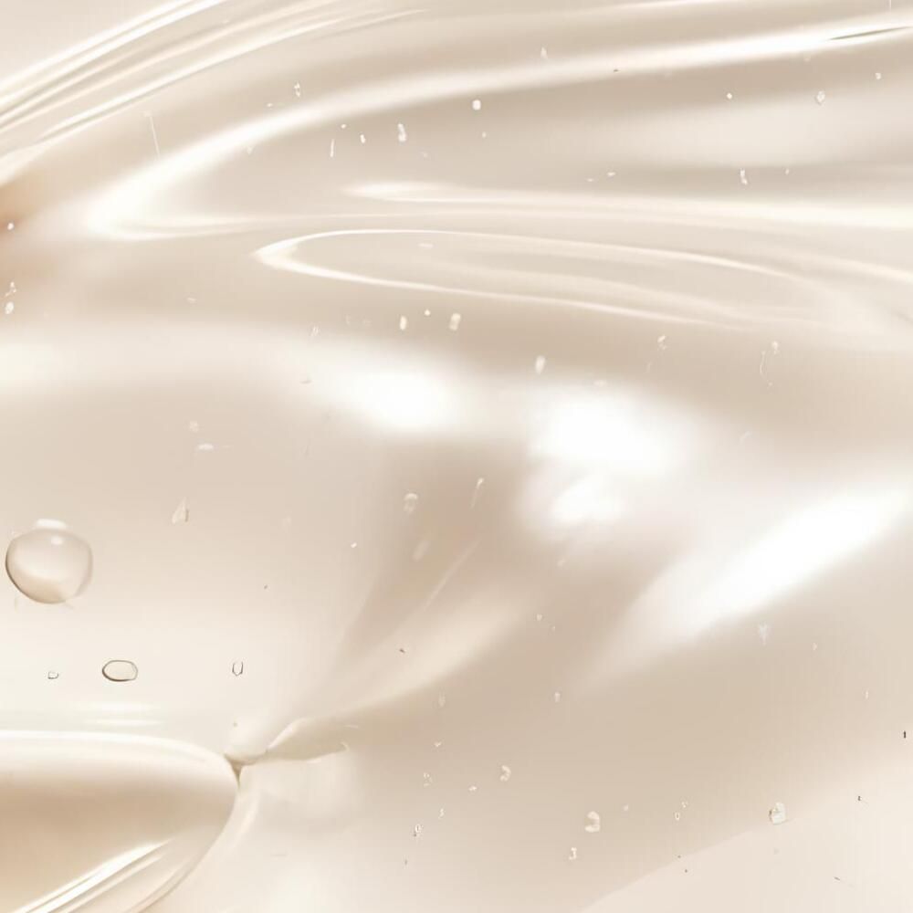 Primo piano di un liquido lucido, color crema, con piccole bolle. Simile a una texture.