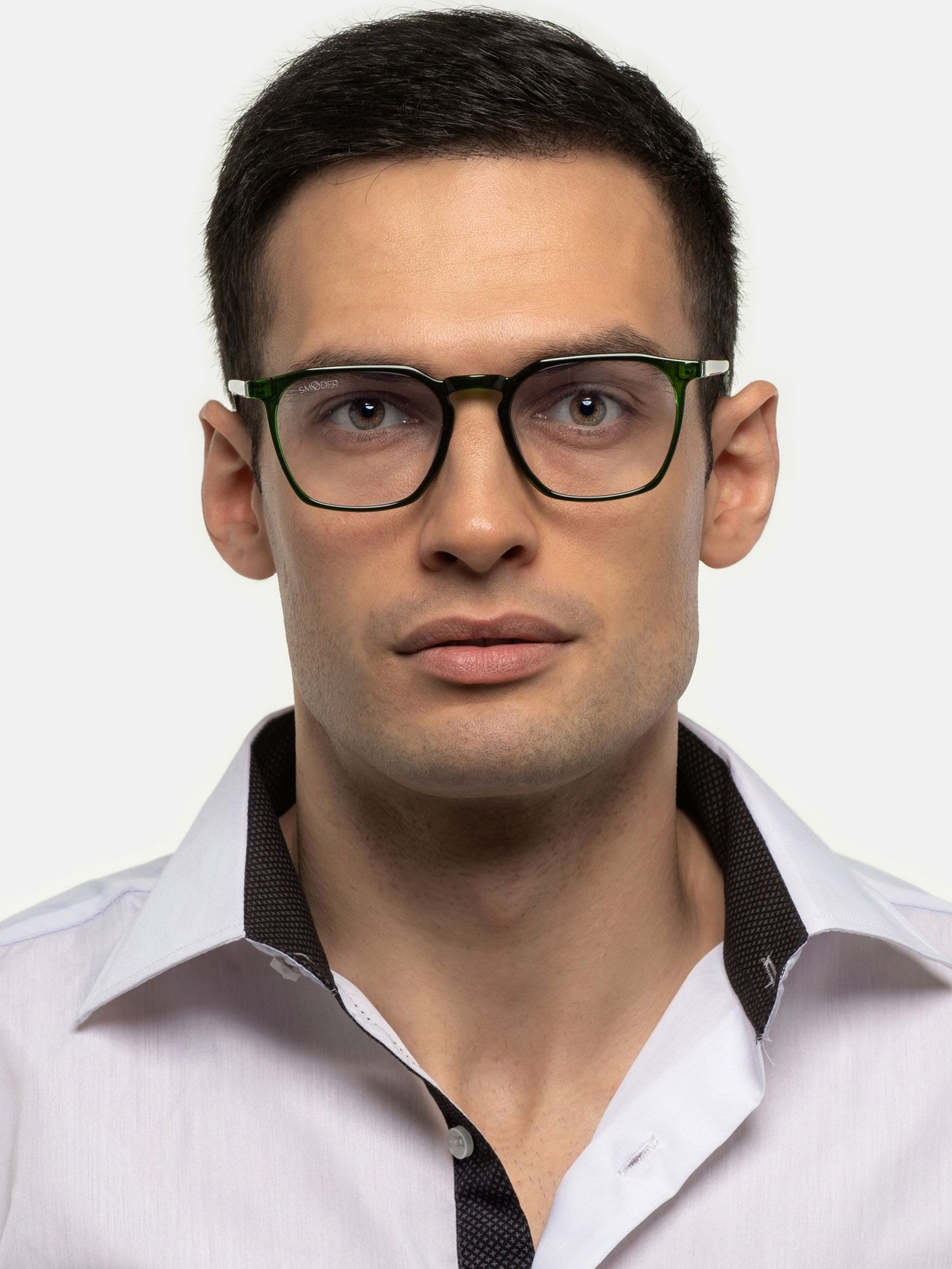 Uomo con occhiali. La montatura è nera con dettagli verdi. L'uomo indossa una camicia bianca.