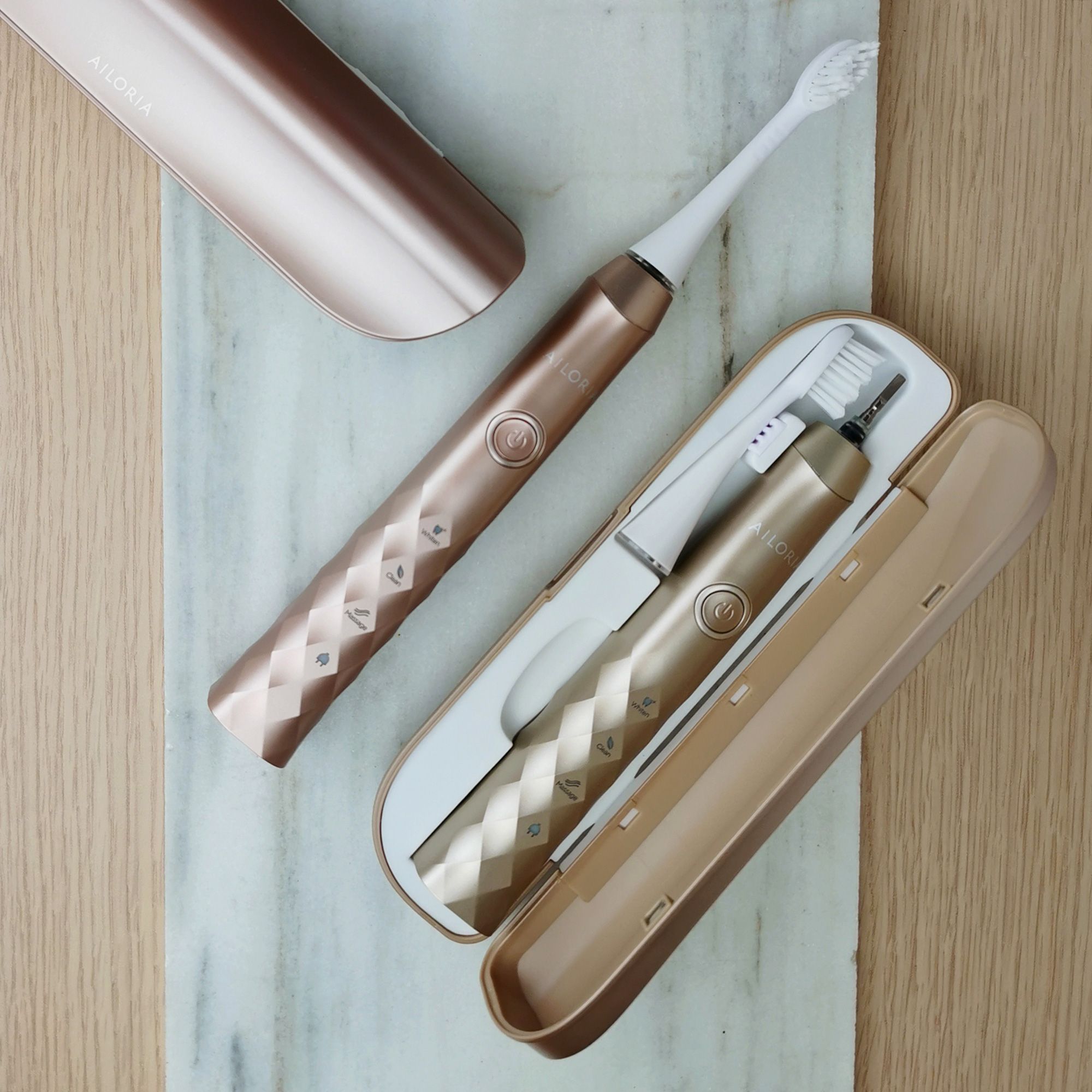 Spazzolino, custodia, stazione di ricarica. Oro rosa. Logo AILORIA. Su lastra di marmo.