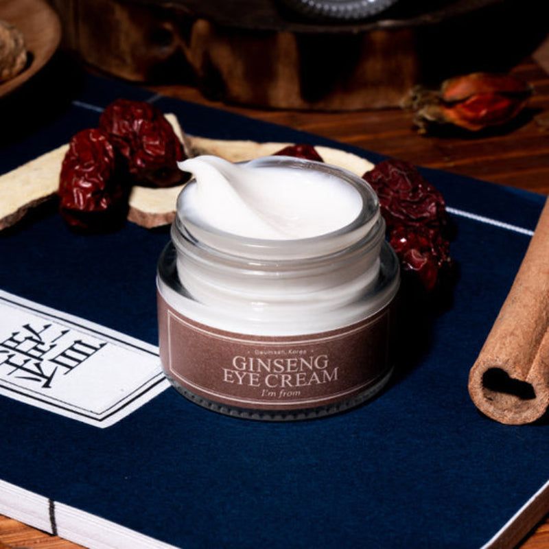 Vasetto di crema per occhi, coperchio marrone, etichetta. Testo: Ginseng Eye Cream, I'm from. Su libro e ingredienti.