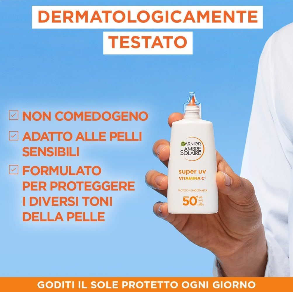 Mano che tiene un flacone Garnier Ambre Solaire Super UV. Testo: Dermatologicamente testato. Non comedogenico. Per pelli sensibili.