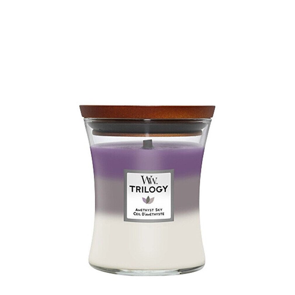 Candela a tre colori con stoppino in legno, in contenitore di vetro con coperchio. Etichetta con logo e testo: Trilogy, Amethyst Sky, Ciel d'Améthyste.