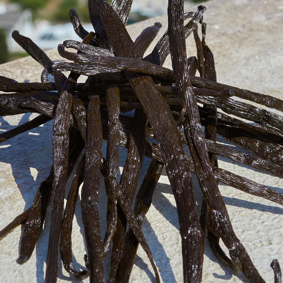 Mucchio di baccelli di vaniglia. I baccelli sono marrone scuro e allungati.