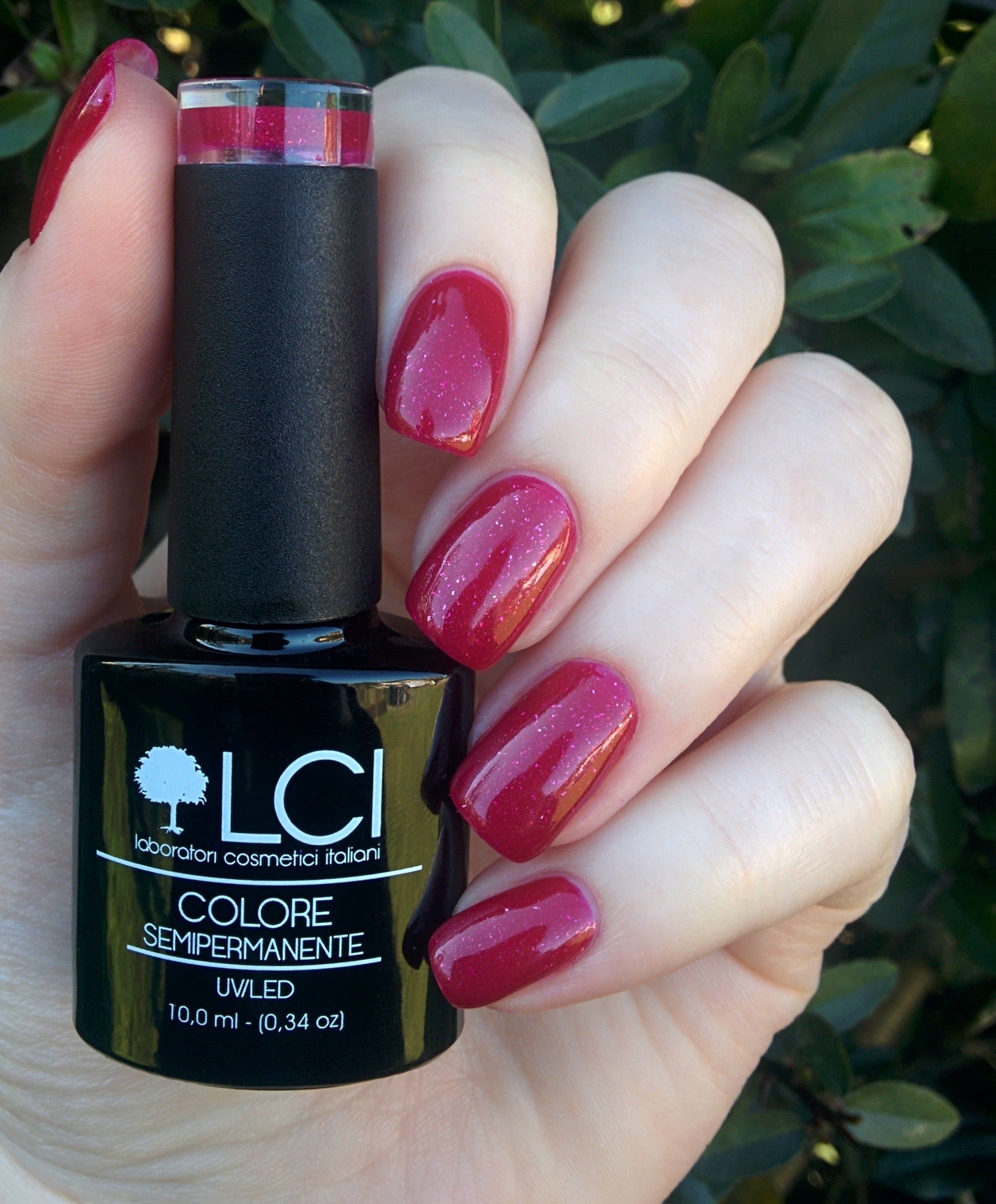 Flacone di smalto in mano. Unghie smaltate Ciliegia Glitter. Logo LCI e nome prodotto. UVLED 10,0 ml.