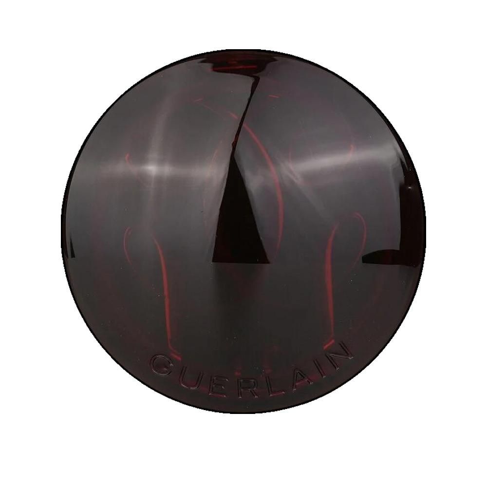Astuccio rotondo marrone di cipria compatta. Coperchio con scritta Guerlain. Superficie lucida.