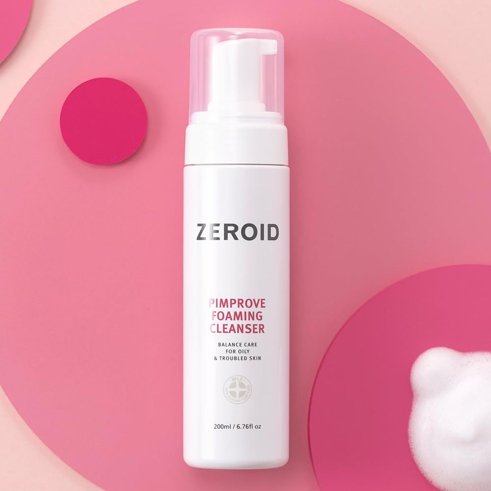 Flacone bianco ZEROID Pimprove Foaming Cleanser con pompa. Nome prodotto e testo. Su sfondo rosa. Schiuma.