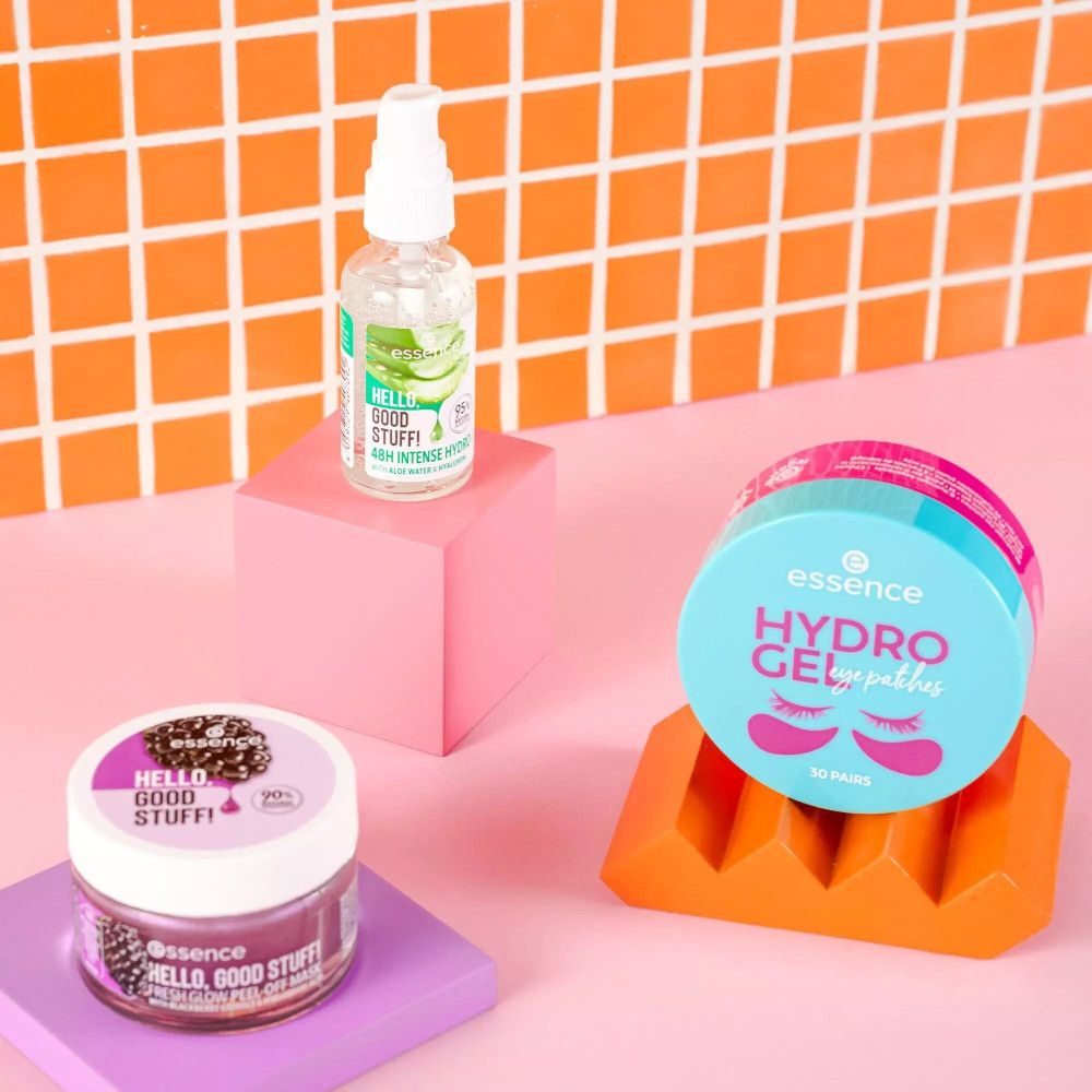 Tre prodotti su piedistalli: flacone di gel, patch occhi e scrub. Sfondo: piastrelle arancioni.