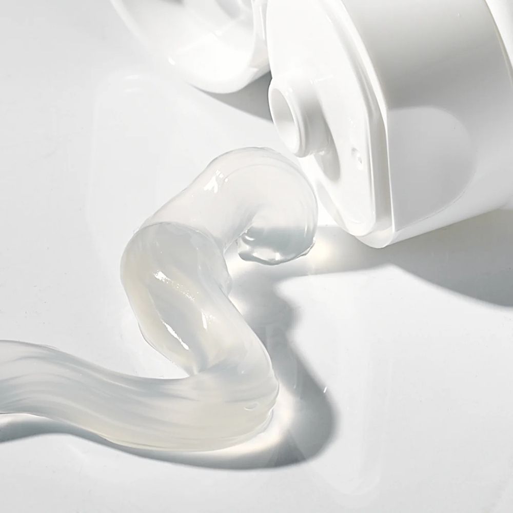 Primo piano di dentifricio che esce da un tubetto. Il dentifricio è trasparente e ha una forma ondulata.