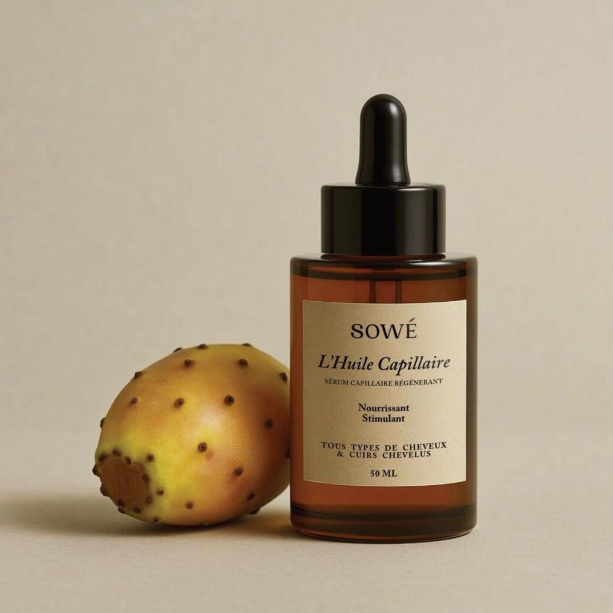 Flacone di vetro marrone con pipetta. Scritta: SOWÉ L'Huile Capillaire, Sérum Capillaire Régénérant. 50 ml. Accanto, un frutto.