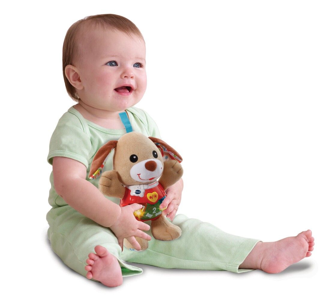 Bambino seduto che tiene in mano un cagnolino di peluche beige con un gilet rosso. Con numeri e luci.