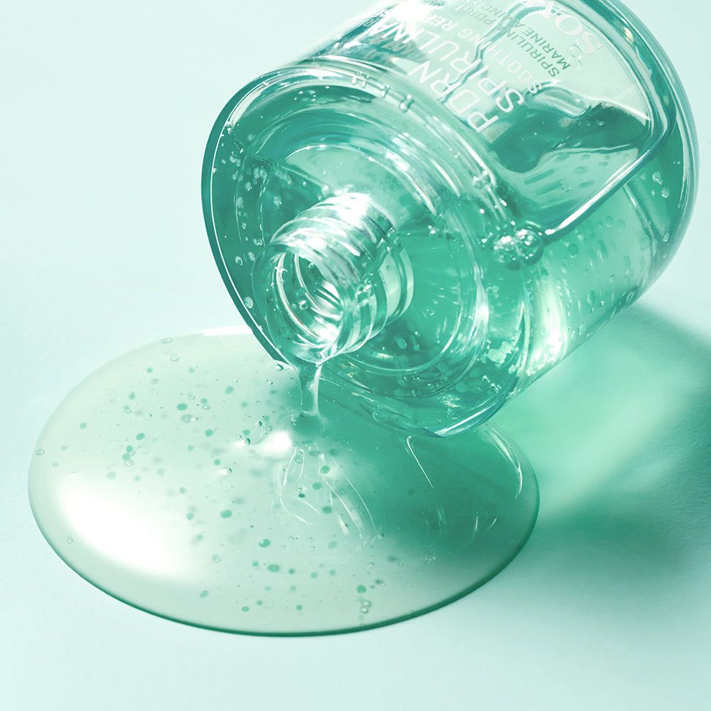 Flacone di siero rovesciato, siero che fuoriesce. Il siero è verdastro con piccole particelle. Sfondo azzurro.