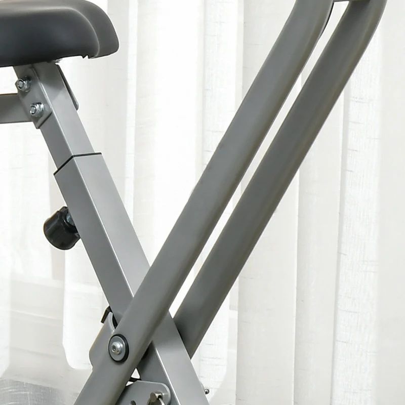 Montanti metallici grigi di una cyclette. Tenda bianca sullo sfondo.