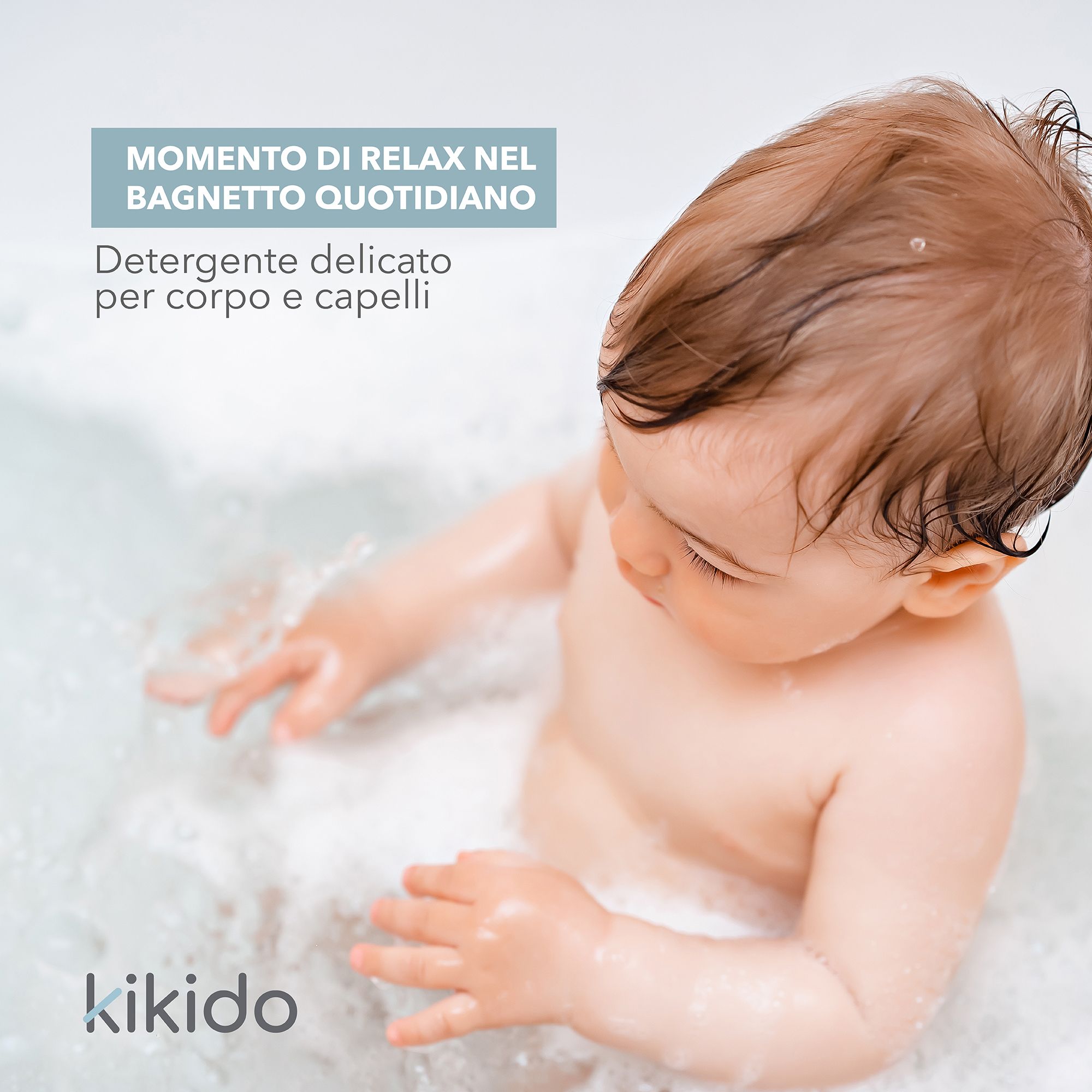 Bambino in vasca da bagno con schiuma. Testo: Kikido, Detersivo delicato per corpo e capelli.