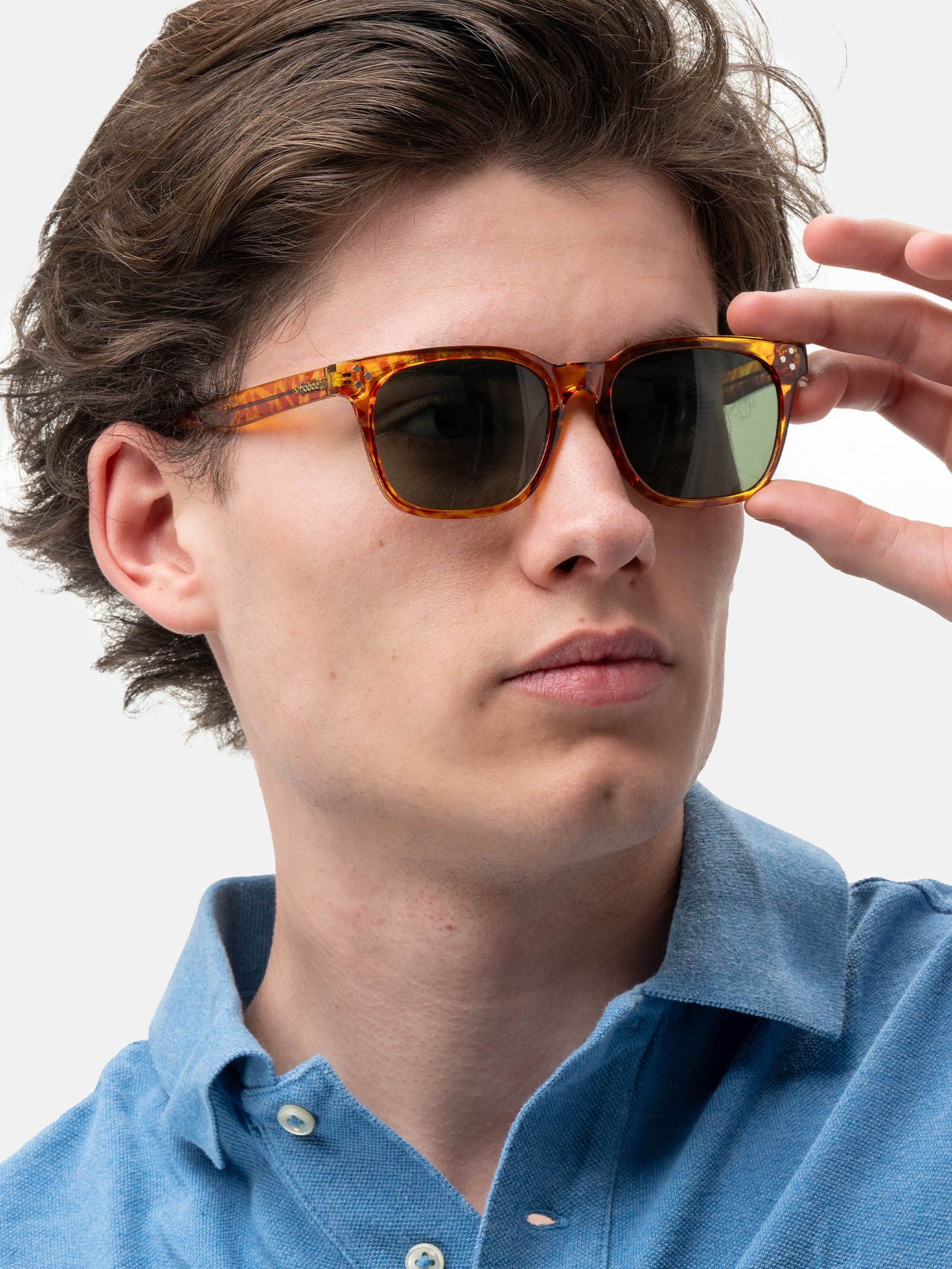 Uomo con occhiali da sole marroni e lenti verdi. Forma rettangolare. Marchio Smooder.