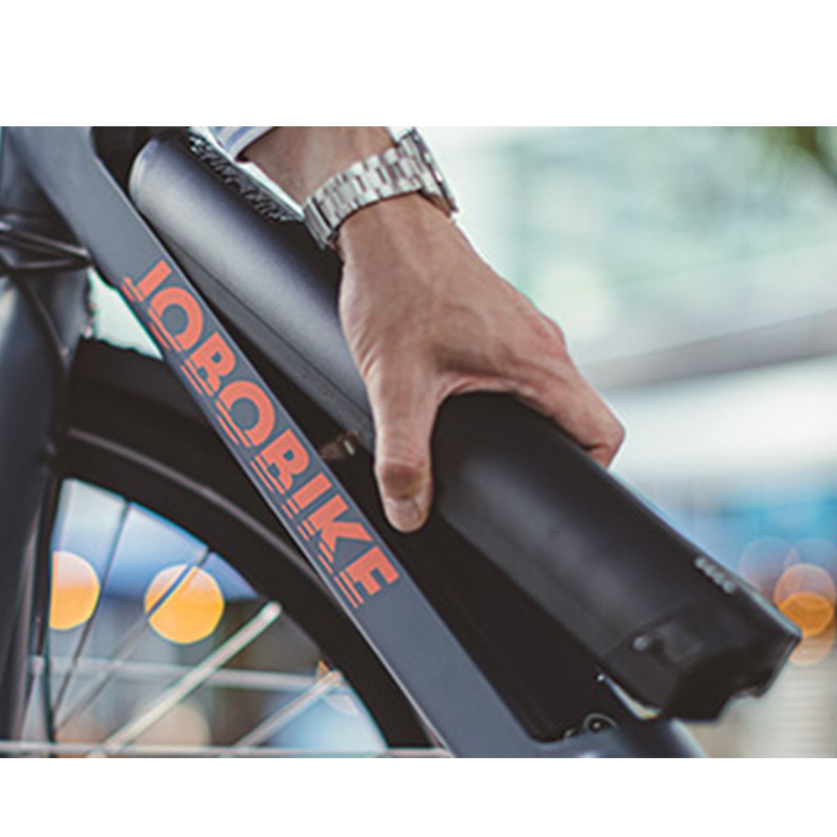 Persona che tiene una batteria nera su un telaio di e-bike. Logo JOBOBIKE visibile.