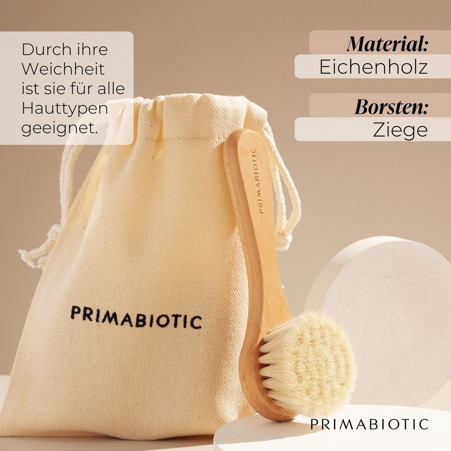 Spazzola per massaggio viso con manico in legno e setole, accanto a un sacchetto. Il sacchetto riporta PRIMABIOTIC. Testo: Materiale: legno di quercia, Setole: capra.