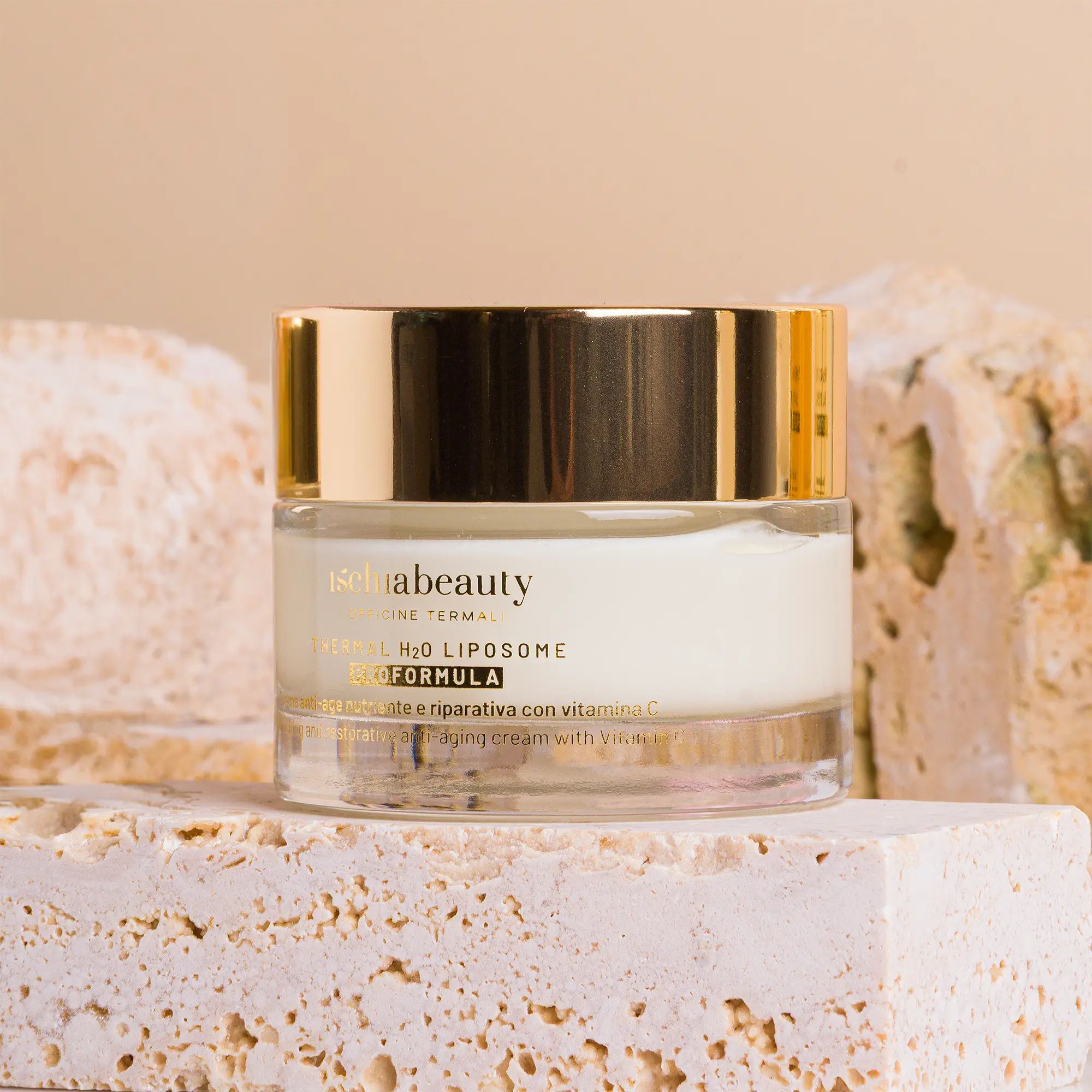 Vaso di crema con coperchio dorato. Scritta ischiabeauty. Posizionato su blocchi di pietra.