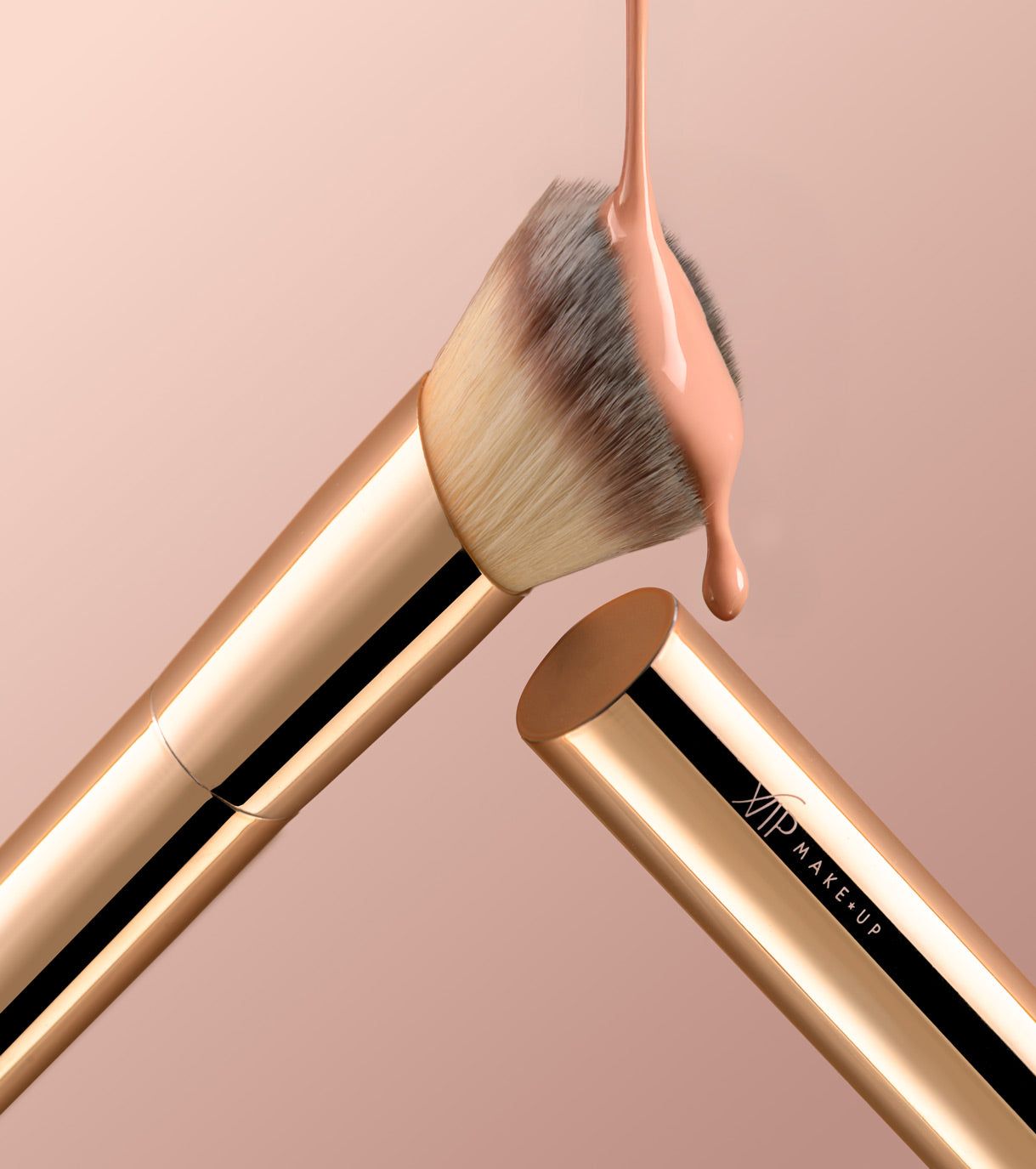 Pennello da trucco dorato con setole piatte, su cui viene applicato fondotinta liquido. Accanto si trova il manico del pennello.