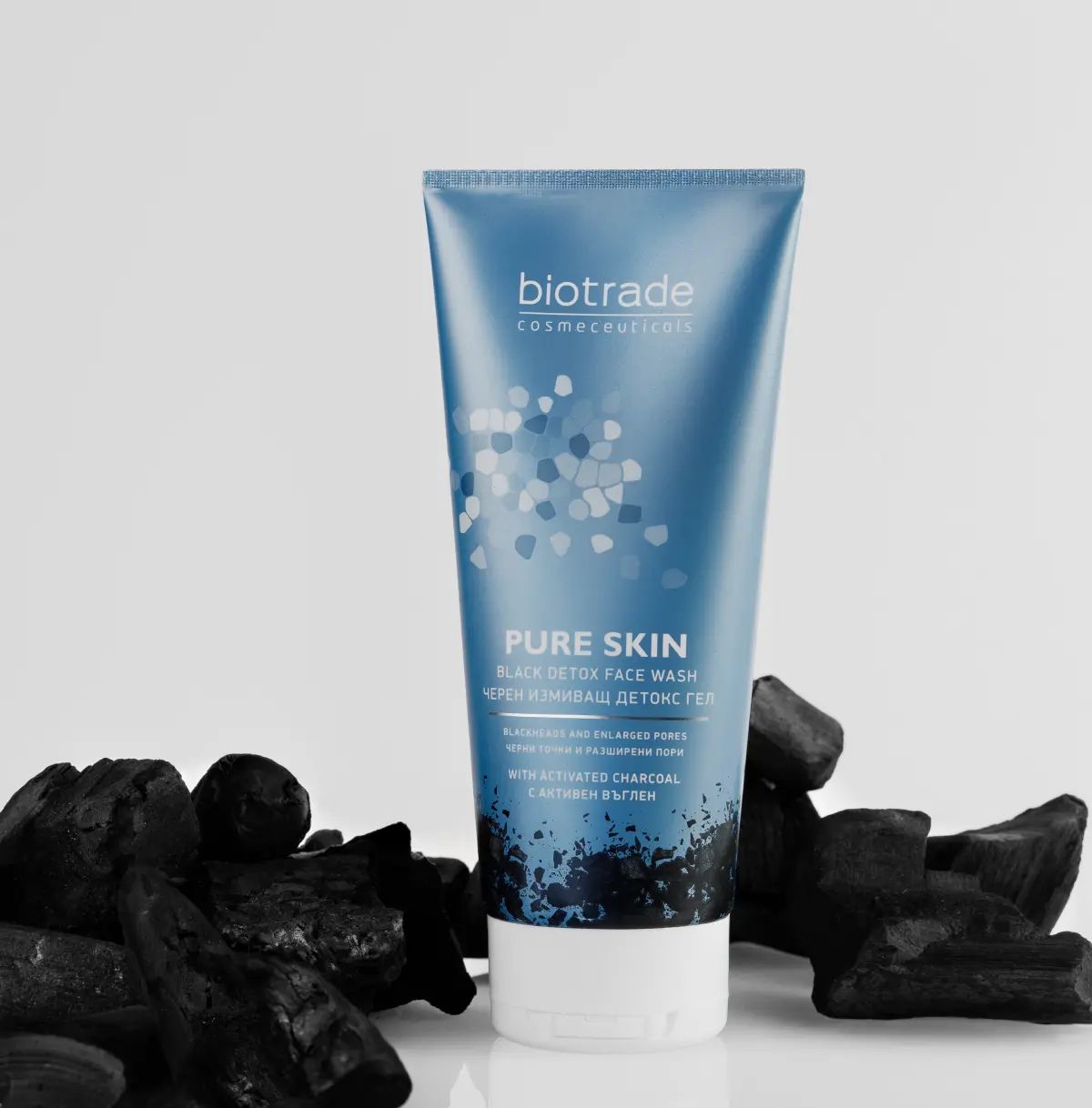 Tubo blu-grigio con tappo bianco, circondato da carbone. Scritta: Biotrade, Pure Skin Black Detox Face Wash.