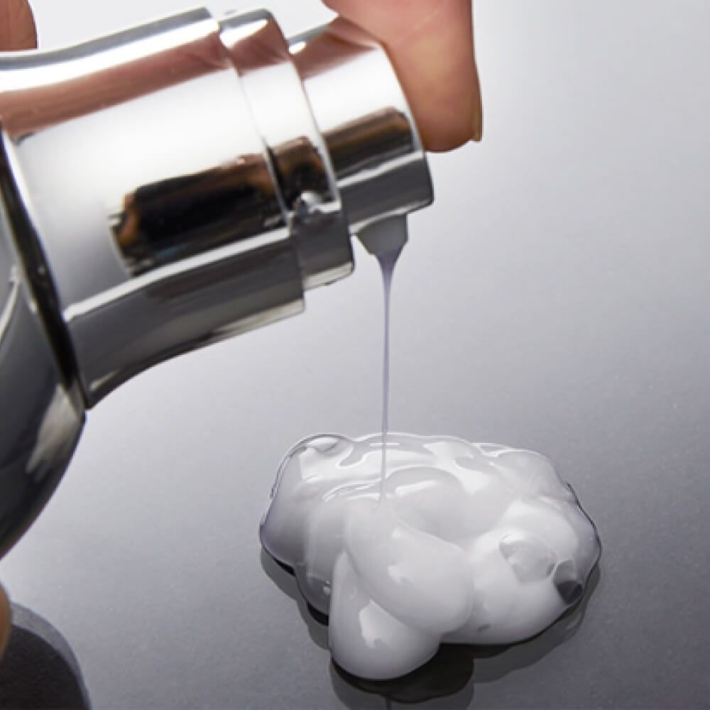 Pompa argentata che eroga un liquido bianco e cremoso.