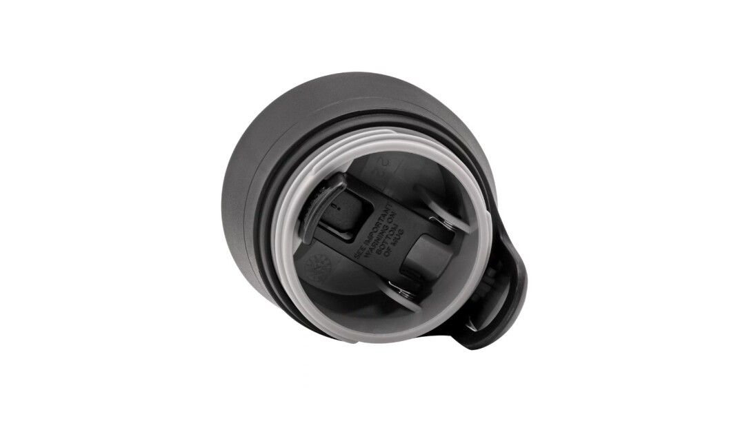 Vista dall'alto del coperchio aperto di un bicchiere termico. Coperchio nero, interno trasparente. Meccanismo visibile.