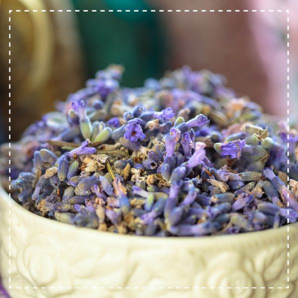 Primo piano di fiori di lavanda in una ciotola color crema. I fiori sono viola e secchi.