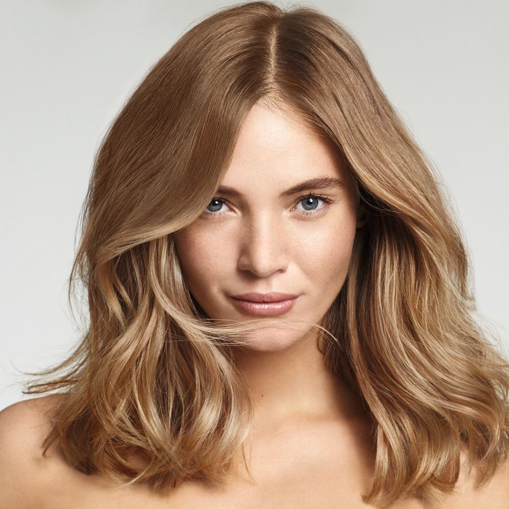 Ritratto di una donna con capelli biondi e mossi. Guarda la fotocamera. Studio luminoso.