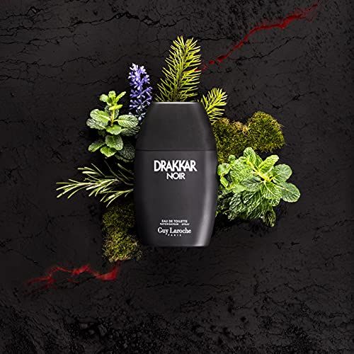 Flacone di profumo nero. Testo: Drakkar Noir Eau de Toilette. Circondato da piante su sfondo nero.