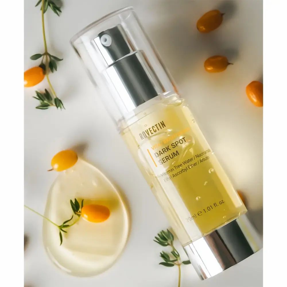 Flacone di siero con erogatore a spruzzo. Scritta: Dark Spot Serum. Contenitore trasparente con liquido giallastro. 30ml.