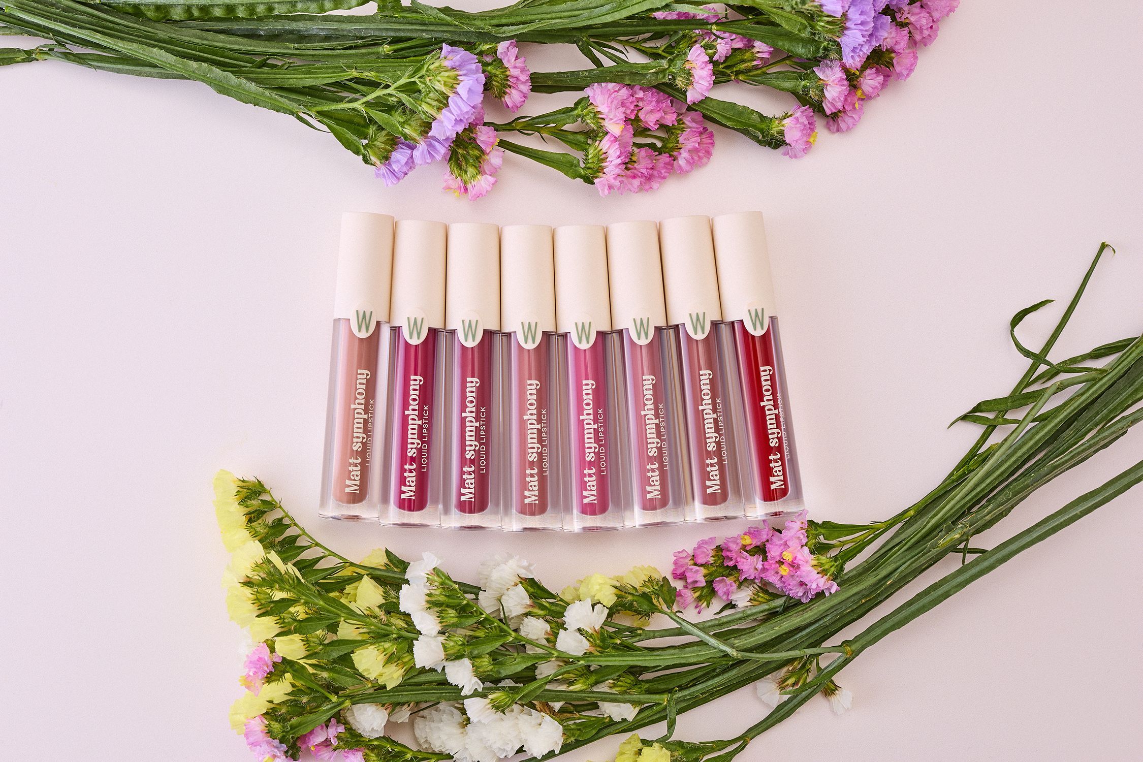 Diversi rossetti liquidi. Scritta: Matt symphony LIQUID LIPSTICK. Decorazione: fiori.