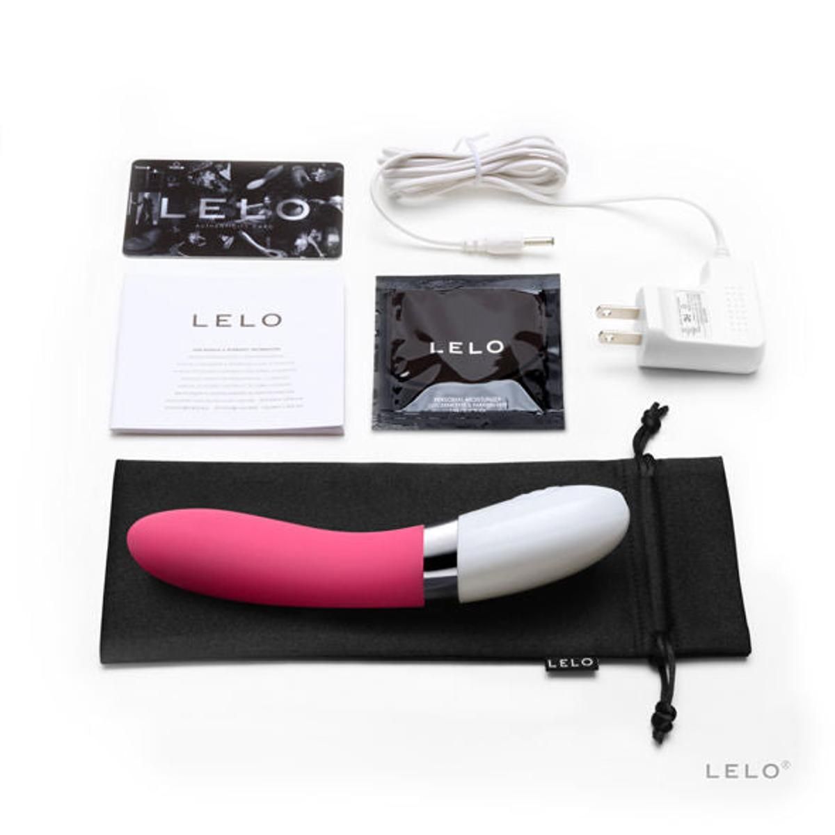 Vibratore rosa e bianco con accessori: cavo di ricarica, adattatore, custodia, scheda, salviette e manuale. Marchio: LELO.