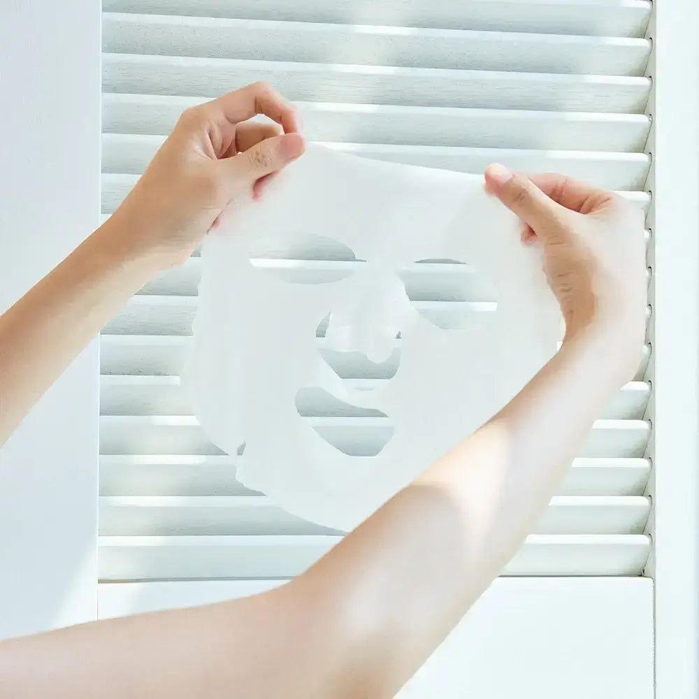Mani che tengono una maschera per il viso bianca. La maschera ha aperture per occhi, naso e bocca.
